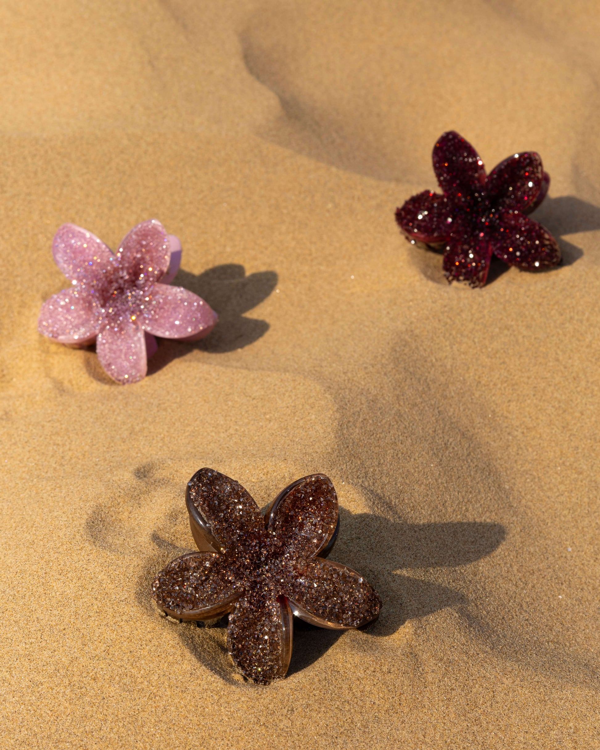 Burgundy, pink and brown diamante floral clips in sand