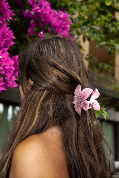 Model in front of pink flowers wearing a pink diamante floral clip in long hair